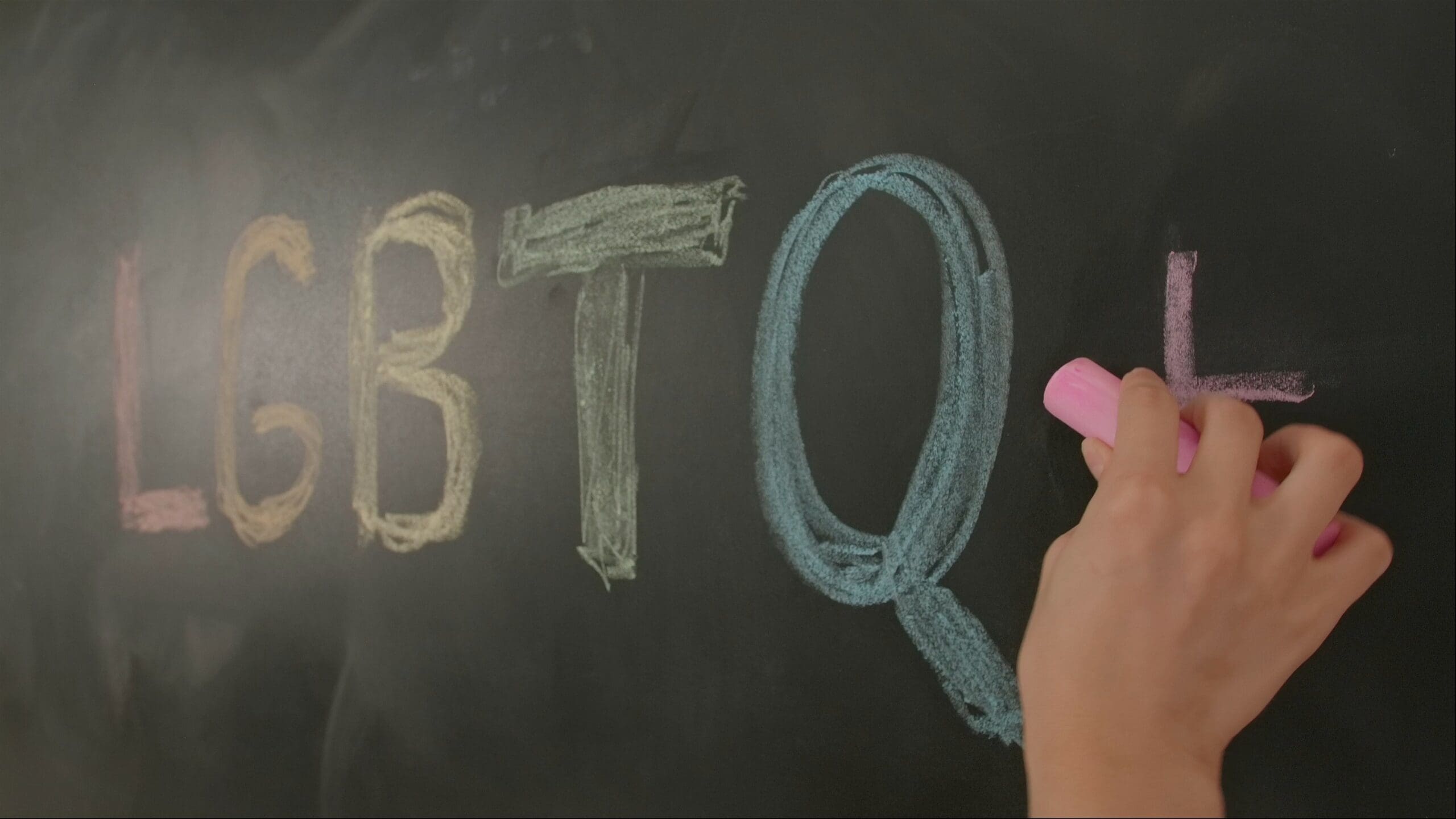 Close up of woman hand writing text letters lgbt with colorful chalks on chalkboard, Diversity and human relationships. Educational concept.